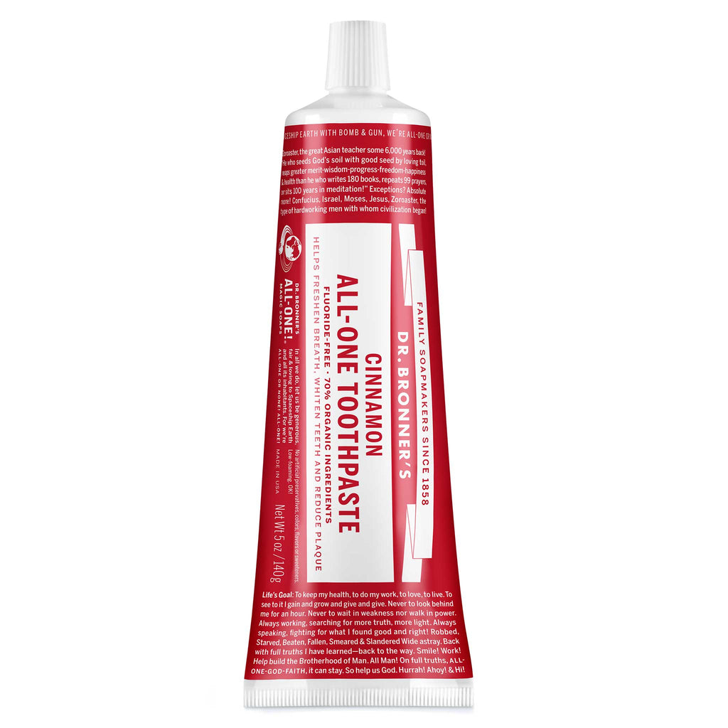 A red and white tube labeled Dr. Bronners All One Cinnamon Toothpaste sits upright, featuring text about fair trade, organic ingredients, and packaging made from sustainable materials [5 oz]