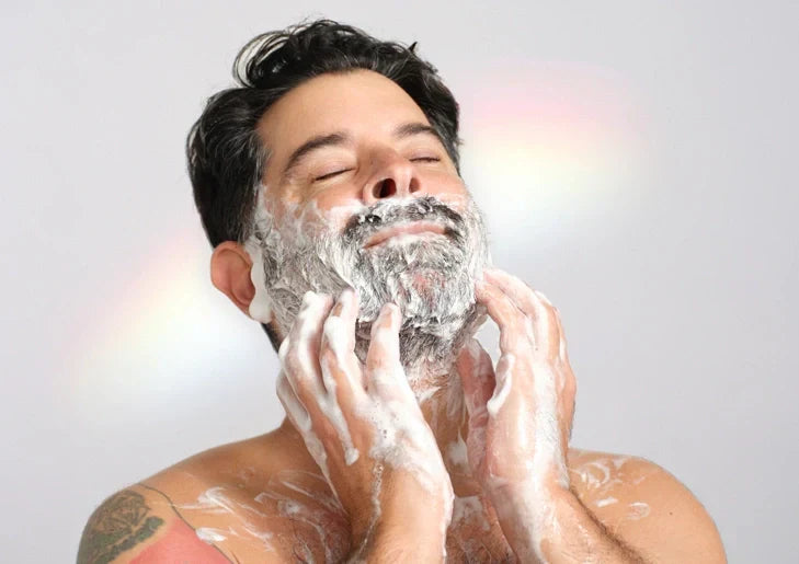 A man, eyes closed, lathers his face and body with foamy soap in a serene setting, highlighting relaxation and self care, emphasizing the benefits of organic, natural products [7 oz]